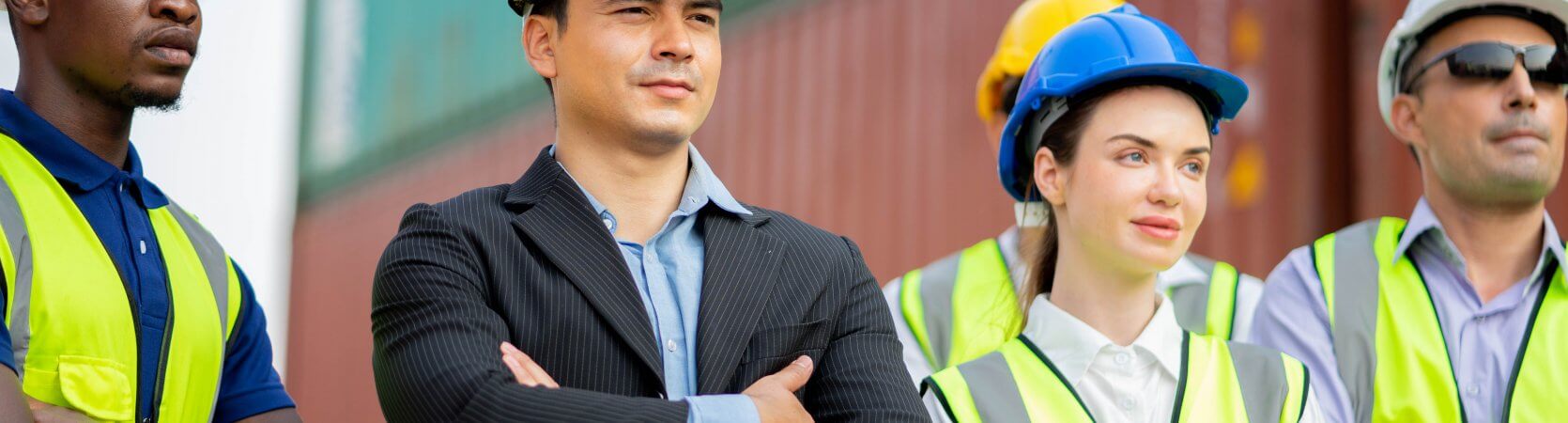 Man in business suit and hard hat standing with construction crew looking pleased.