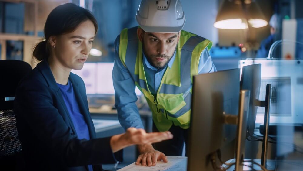 Engineer at computer speaking with construction manager